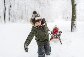 Fototapeta na wymiar Little kids enjoy a sleigh ride. Child sledding. Children play outdoors in snow.