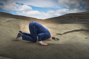 Naklejka na ściany i meble Businessman hiding his head in sand escaping from problems