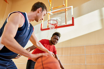 Naklejka premium Concentrated confident young African-American man controlling basketball competitor dribbling trying to score point on court
