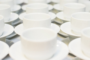 Many rows of white coffee cup with saucer and teaspoon on table