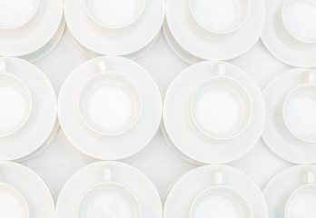 Many rows of white coffee cup with saucer and teaspoon on table, view from above