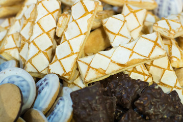 Background of mixed biscuits covered with milk, dark and white chocolate, top view, flat lay