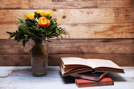 Ranunculus Flower In A Vase Beside A Stack Of Books