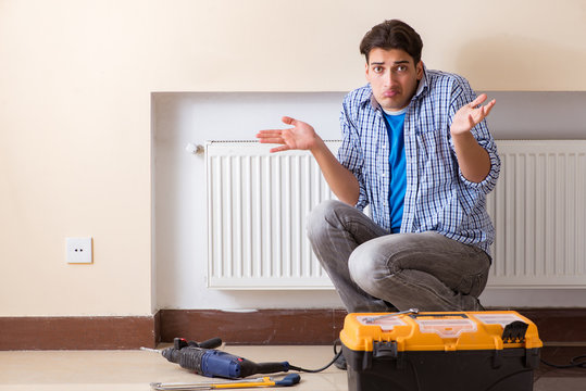 Young repairman contractor repairing heating panel 