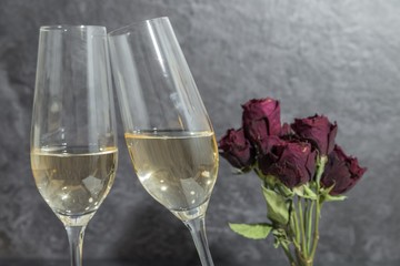 Champagner Gläser mit einem Blumenstrauß aus getrockneten roten Rosen