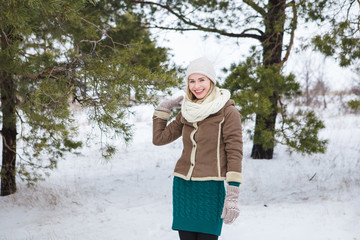 Attractive girl holding a lump of snow, looking at the camera and smiling outdoors in winter....