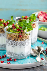 Layered chia pudding parfait with kiwi fruit, pomegranate, granola and yogurt, healthy breakfast