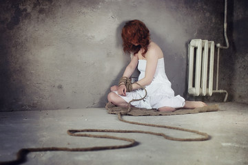 Young girl tied up on the floor. The abducted girl. The victim o