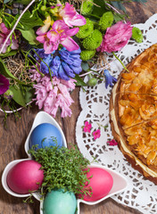 Arrangement mit Ostereiern, Blüten und Kuchen auf Holztisch