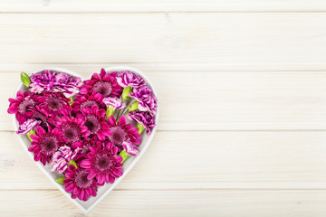 garden flowers in heart shape on white wooden rustic table background with copy space for your text. vintage card, flat lay, top view. wedding, valentines day, mothers day or womens day composition