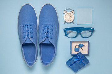 High angle view of hipster man blue set of sneakers, alarm clock, sticky notes, eyeglasses and gift box with padlock.