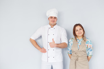 Chef men and woman wearing apron isolated on light background. Couple at work. Thumb up