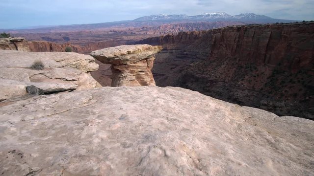 Walking to the edge of a steep canyon viewing rock spire in Long Canyon near Moab Utah.
