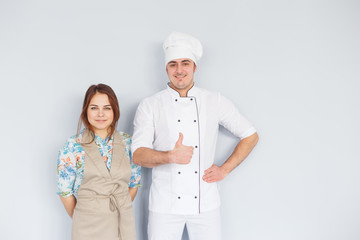 Chef men and woman wearing apron isolated on light background. Couple at work. Thumb up