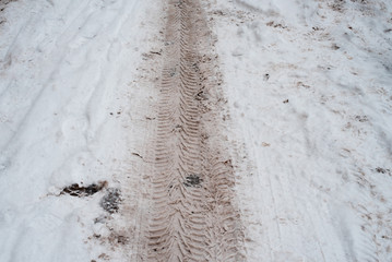 Dirty traces of the tread on white snow-covered road. In the winter traces of snow from the car.