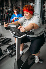 Fototapeta na wymiar Overweight woman, workout on exercise bike in gym