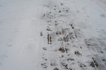 In winter, a snow-covered paving block in city. Footprints from boots in the snow. Sidewalk in the winter in the snow.
