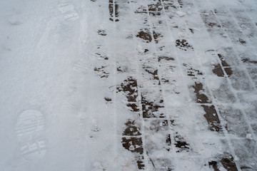 In winter, a snow-covered paving block in the city. Footprints from boots in the snow. Sidewalk in the winter in the snow.