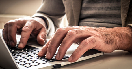 Hands mature businessman on laptop. Close up.
