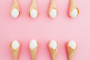 Frame made of Easter white eggs in waffle cone on pastel pink background. Top view, Flat lay. Easter holiday concept.