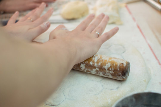 Close-up view of the hands rolling out the dough with rolling pin for homemade potstickers. Motion blur.