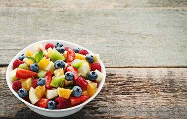 Fresh fruit salad in bowl on grey wooden table