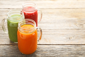 Vegetables smoothie in jars on grey wooden table