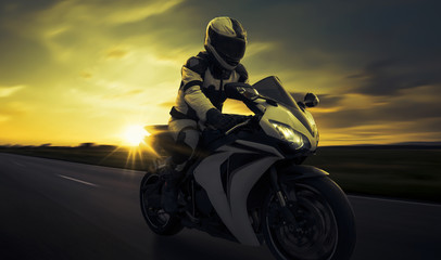 schneller Motorradfahrer auf Straße im Sonnenuntergang