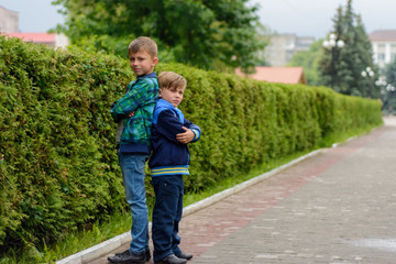 Fototapeta premium Two little brothers standing in the streets of their city back to back