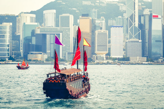 Scenic daytime skyline of Hong Kong island with skyscrapers and traditional boats sailing.