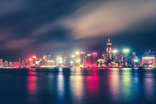 Scenic nighttime skyline of Hong Kong island, China, with skyscrapers and city illuminations. Victoria harbor at night. Multicolored travel background.