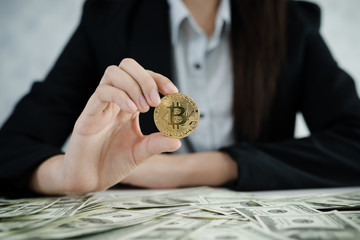Hands of business women holding Bitcoin and money dollar pile on the table.
