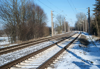 Fototapeta premium Schneebedeckte Bahngleise im Winter bei Sonnenschein und blauem Himmel, Bahnverkehr 