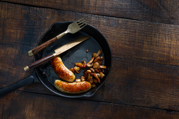 Fried chicken sausages with mushrooms in pan, top view