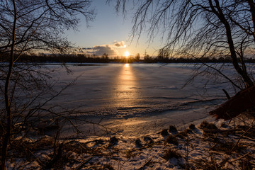 colorful winter sunset with light rays coming through the trees