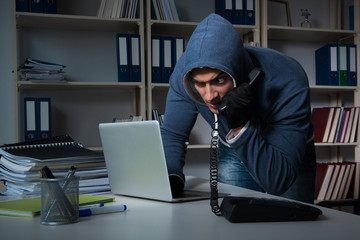 Young hacker hacking into computer at night