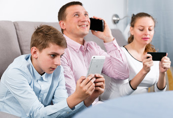 Parents and son using phones