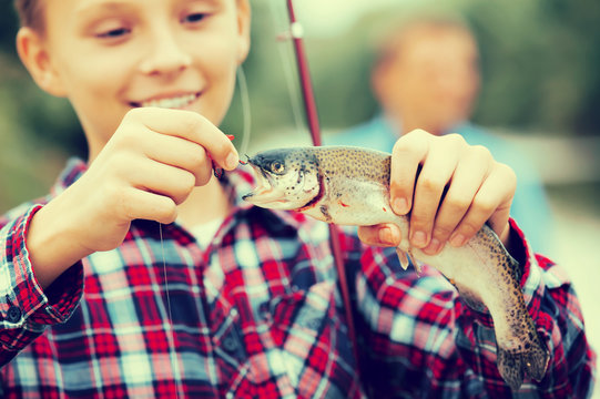Happy teenage boy releasing catch on hook fish