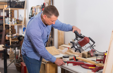 carpenter with  fret saw cutting wood plank at workshop
