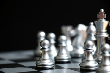 Silver pawn is on the first move in chess game on black background (Concept for business decision,...