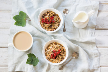 Summer healthy breakfast of granola, muesli with milk jug with red currant as decor. Top view.