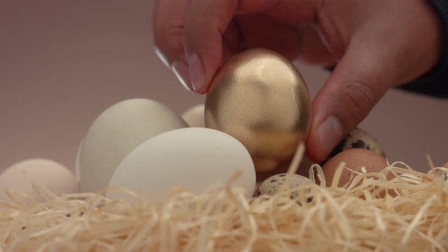 closeup how man's hand take away a golden egg. Easter eggs