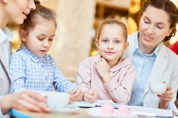 Pretty girl, her friend and mother spending time in cafe while having break