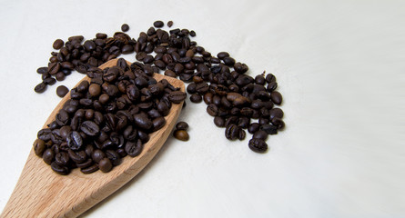 Fototapeta na wymiar close up of roasted coffee beans on a wood spoon with white background with space for text.