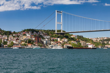 View of Fatih Sultan Mehmet Bridge which is localed on Bosphorus strait . Ships passing through bridge connecting Europe and Asia. Sunny day with background of cloudy blue sky. Istanbul. Turkey.