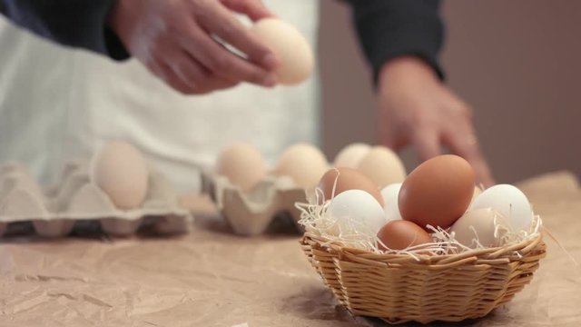 man takes eggs from the basket and put it to the baxoes. Small farmm worker