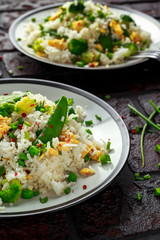 Fried rice with vegetables, broccoli, peas and eggs in a plate. soy sauce. healthy food