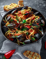 Homemade Pasta Spaghetti with mussels, tomato sauce, chilli and parsley in rustic skillet, pan. sea food meal
