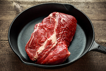 Fresh Raw braising steak in rustic skillet.