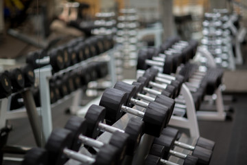 Fototapeta na wymiar Rows of sports equipment for pumping biceps in contemporary gym